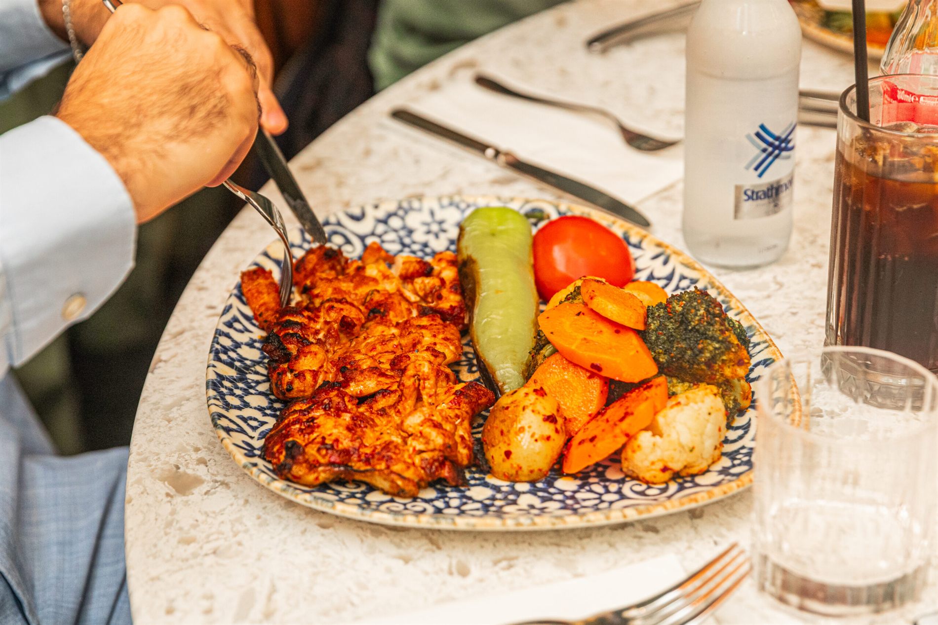 A server plating a dish at the table
