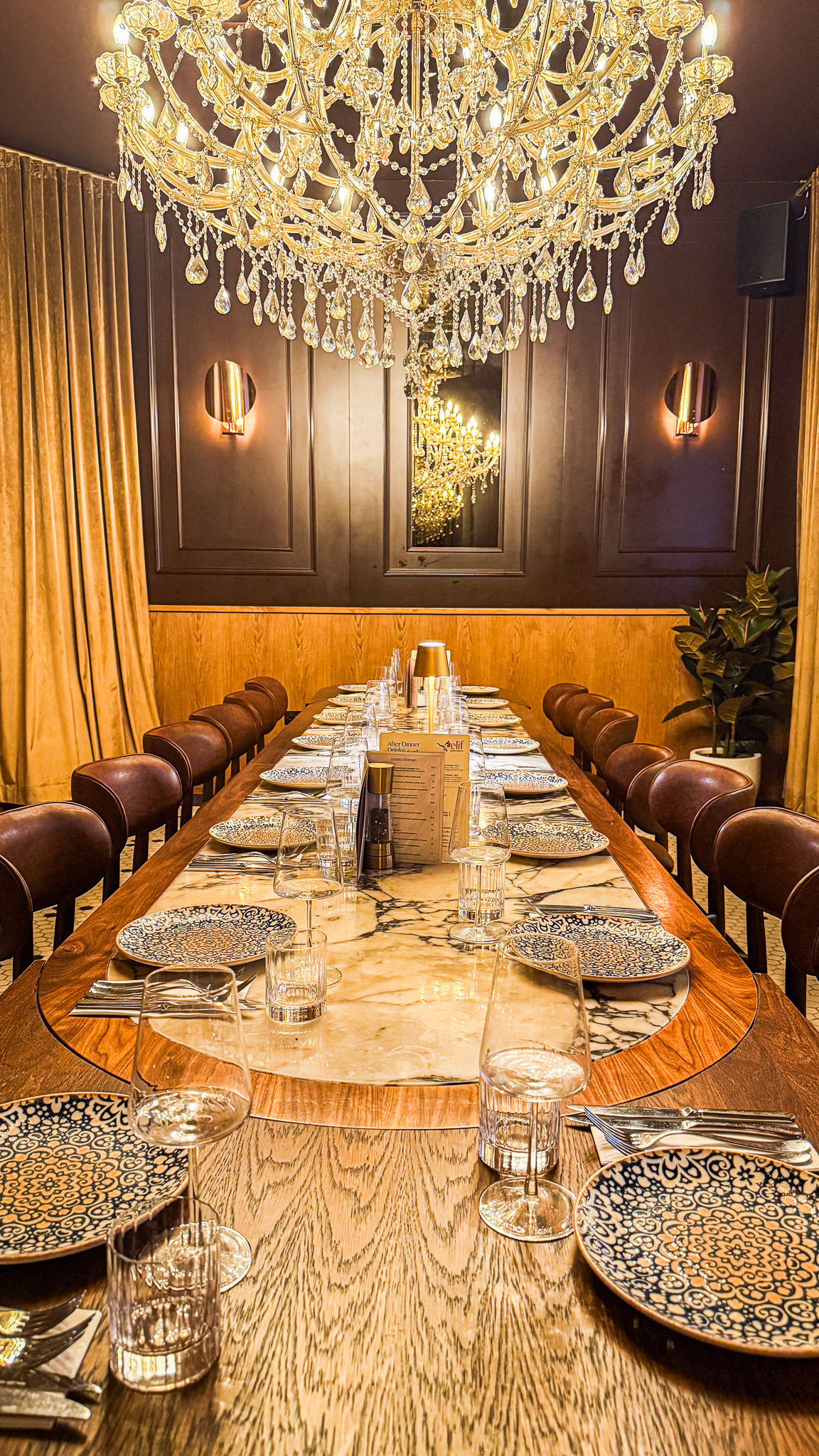 A long marble table laid for a party beneath a crystal chandelier